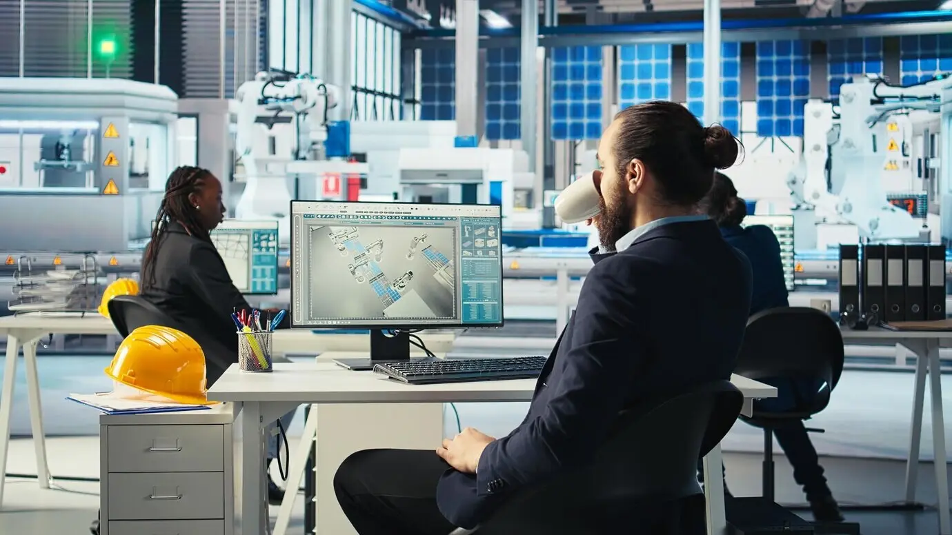 Ingeniero en una fábrica fotovoltaica bebiendo café mientras analiza datos.