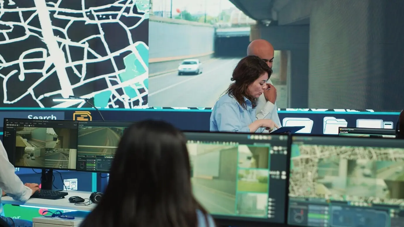 Equipo diverso de empleados de una agencia que sigue camiones de reparto mediante coordenadas GPS.